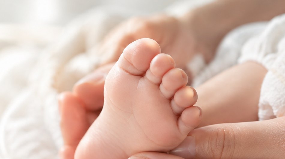 Pieds de nouveau-né tenus dans les mains de sa maman